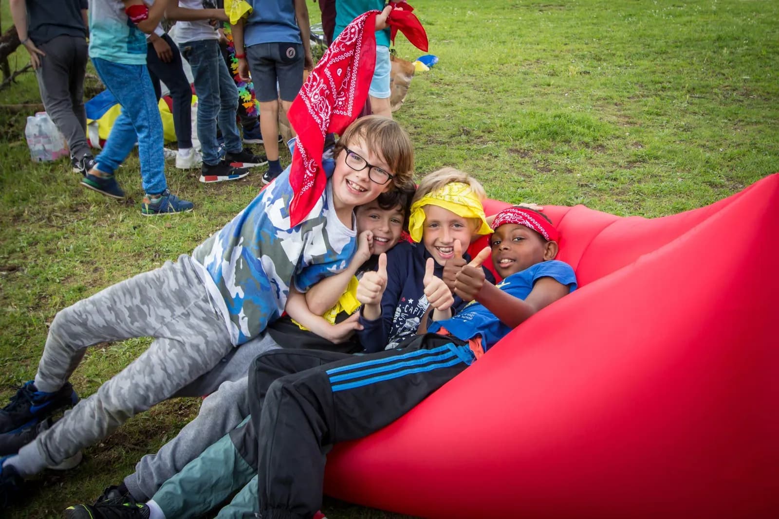 Des enfants allongés sur un coussin gonflable rouge dans un parc