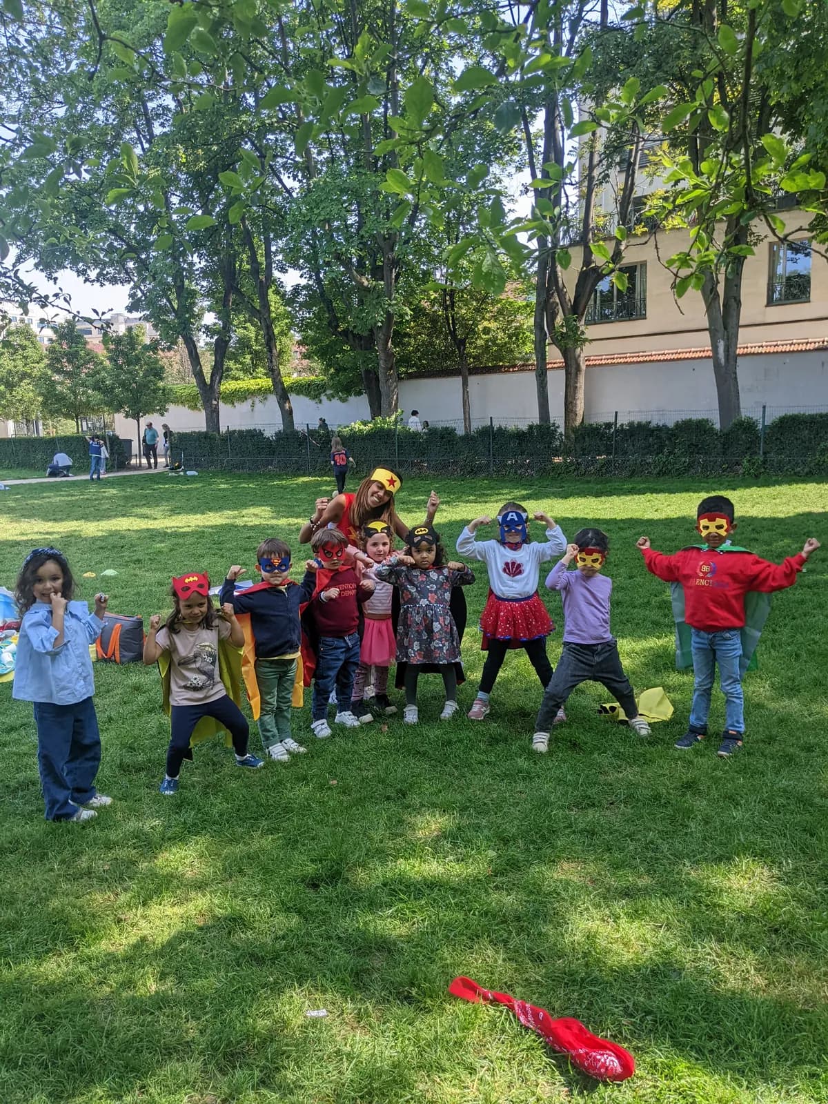 Un groupe d’enfants masqués et costumés saute en ligne sur la pelouse d’un jardin