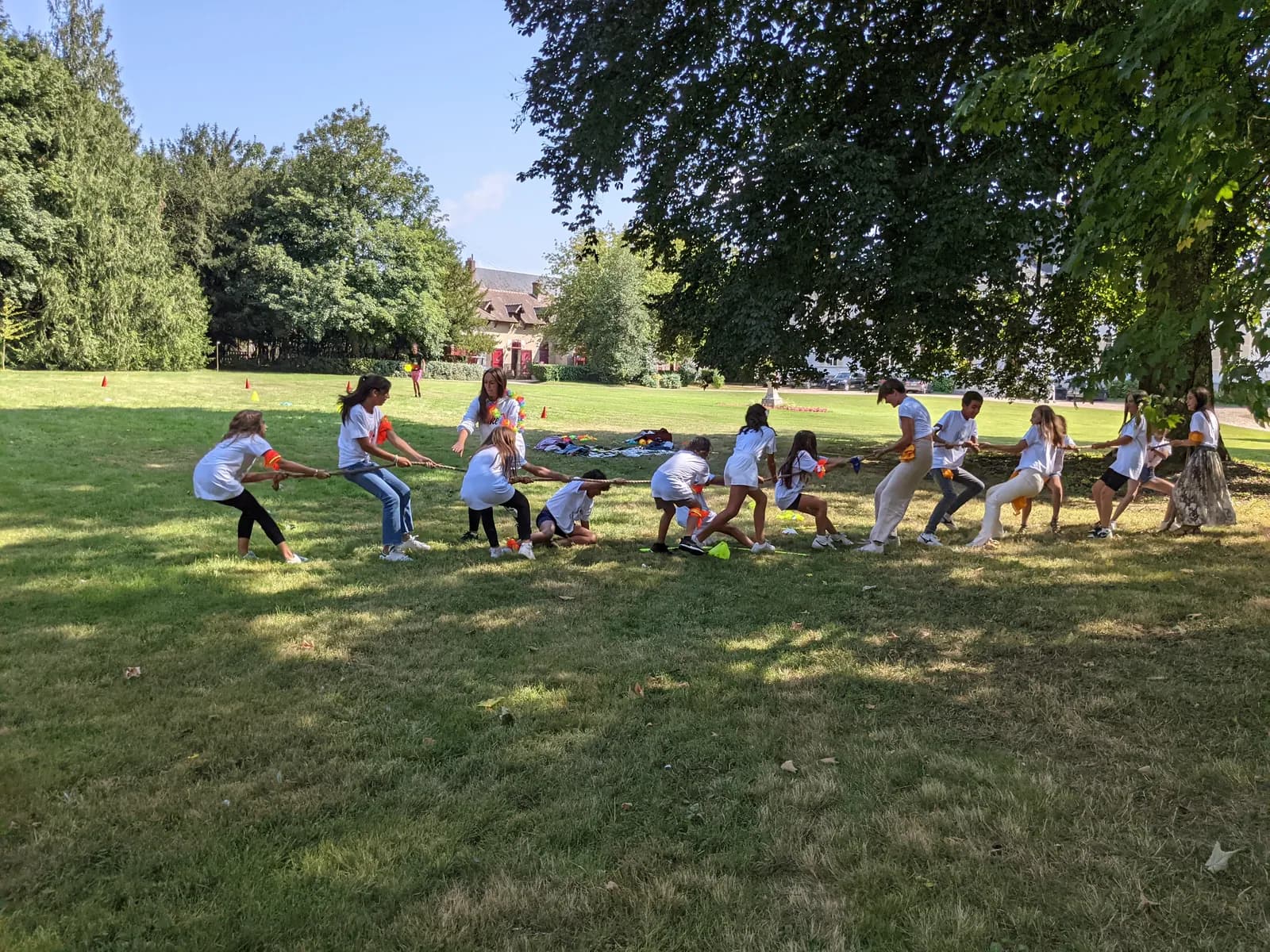 Children playing tug of war on a park lawn during a birthday party