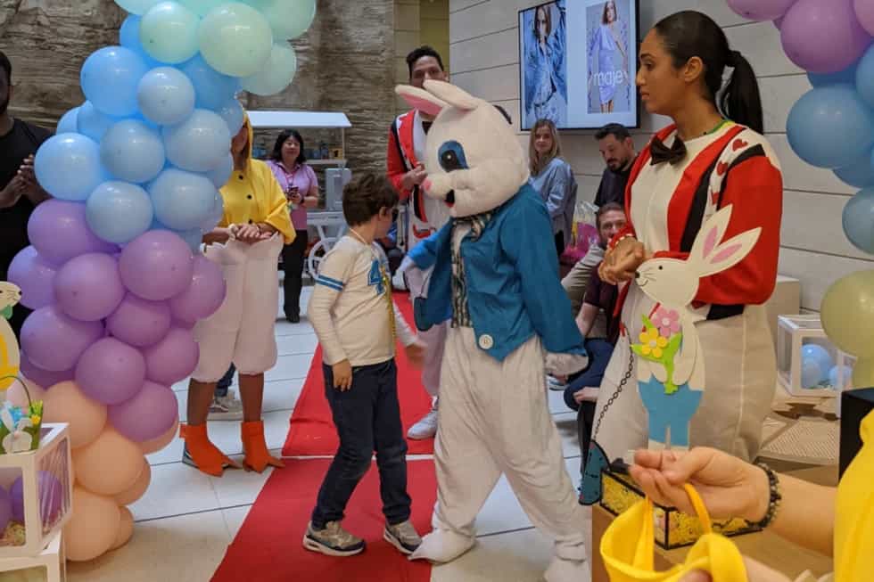 Enfant avançant sur un tapis rouge vers un animateur costumé en lapin lors d’une animation de Pâques en entreprise
