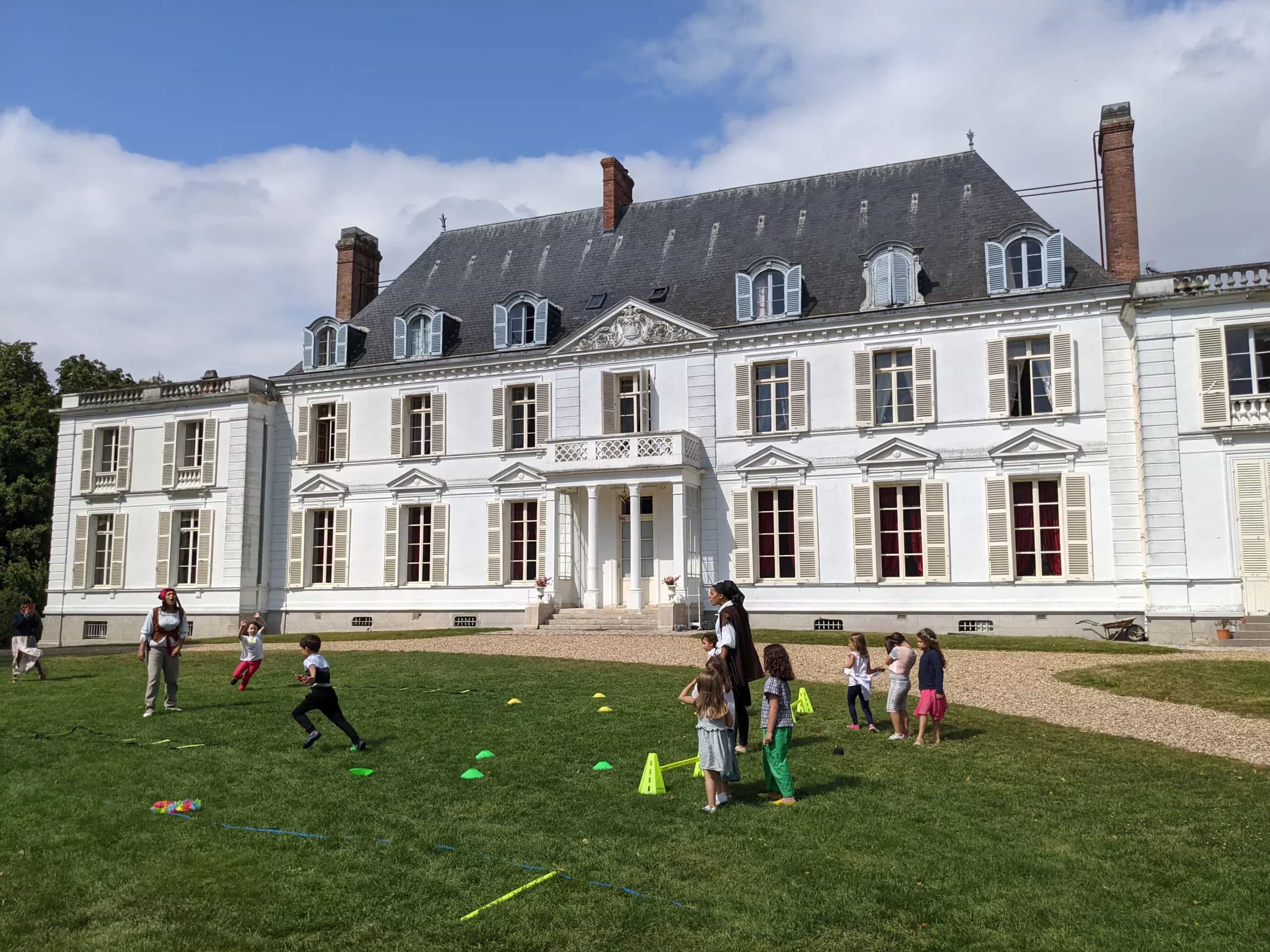 Enfants en pleine course sur la pelouse d’un château, encadrés par deux animateurs Kidays pendant un mariage