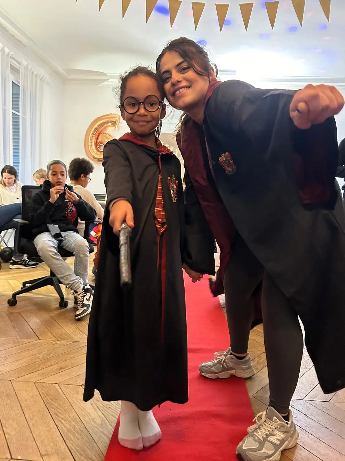 A child in a wizard cape posing with her host during a birthday party